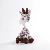 Crocheted giraffe toy with white and brown pattern on a light gray background