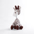 Crocheted giraffe toy with white and brown pattern on a light gray background